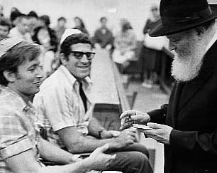 The Rebbe talks and distributes dollars for charity to the wounded servicemen of the Israeli Defense Force